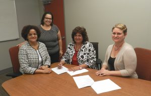 (L-R) Minister for Education Hon. Tara Rivers, JP, Manager Scholarship Secretariat Mrs. Deirdre Carmola, CIIA Secretary Mrs. Linda Key and CIIA Subcommittee Member Mrs. Laverne Jackson sign the MOU for the new Cayman Islands Insurance Association Scholarship.